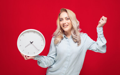 Happy young woman with smile face holding wall clock, isolated on red background. Exhilarated girl