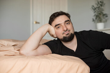 Handsome smiling young man sitting in the bedroom