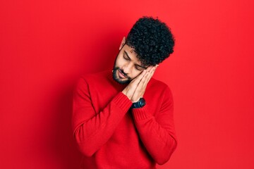 Fototapeta na wymiar Young arab man with beard wearing casual red sweater sleeping tired dreaming and posing with hands together while smiling with closed eyes.