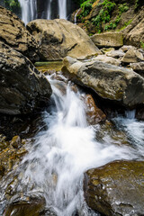Naklejka na ściany i meble The stones under the waterfall, close-up waterfall as background.
