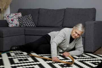 Senior woman lying on the floor in living room. Woman fell on the floor because of heart attack,...
