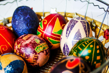 Easter eggs. Close-up round basket with colorful easter eggs on white background. Easter decoration with crafted nest. Perfect colorful handmade easter eggs. Selective focus