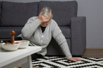 Senior woman lying on the floor in living room. Woman fell on the floor because of heart attack,...