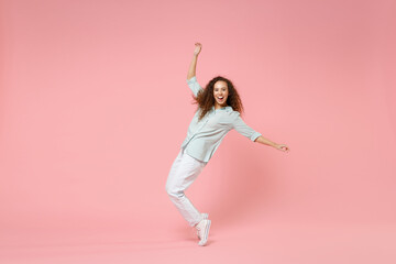 Fototapeta na wymiar Full length young black african american happy smiling friendly curly woman in blue shirt look camera standing on toes leaning back dancing have fun isolated on pastel pink background studio portrait.