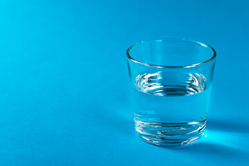 A glass with water in a blue colors background.
