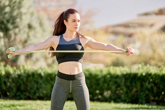 Young Woman With Long Black Hair Working Out In A Park With An Elastic Band