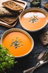 Vegetable creamy healthy soup with pumpkin seeds on a kitchen table.