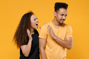 Young couple friends together family african irritated angry nervous woman man 20s in black t-shirt scream shout arguing with disregarded boyfriend isolated on yellow color background studio portrait.