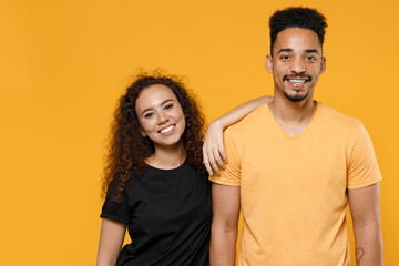 Fototapeta premium Young happy couple friends together family african smiling lovely woman man 20s wear black t-shirt girlfiend leaning on boyfriend isolated on yellow background studio portrait. Relationship concept.