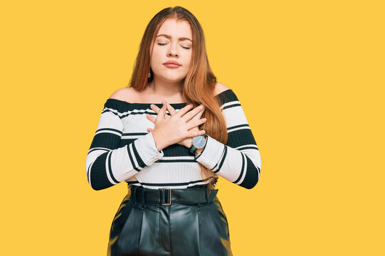 Young beautiful redhead woman wearing elegant clothes smiling with hands on chest with closed eyes and grateful gesture on face. health concept.