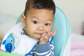 Portrait of a newborn Asian baby sucking their fingers 