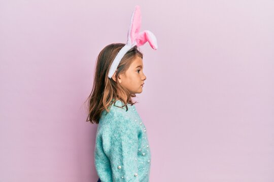 Little beautiful girl wearing cute easter bunny ears looking to side, relax profile pose with natural face with confident smile.