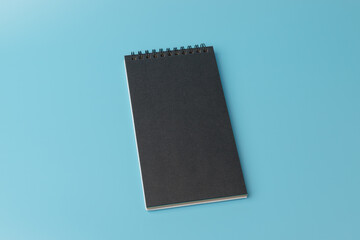 Black notebook  on blue background. top view, copy space