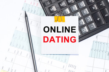 Text ONLINE DATING on NOTEBOOK ,NOTEBOOK, CALCULATOR PENCIL on white background.