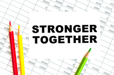 Business concept. text STRONGER TOGETHER sheet of paper for notes, pencils in the background
