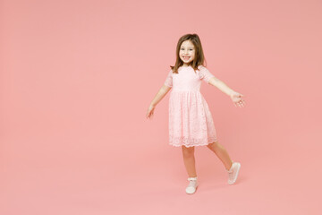 Full body length little cute kid girl 5-6 years old wears rosy dress have fun walk go step isolated on pastel pink background child studio portrait. Mother's Day love family people lifestyle concept.