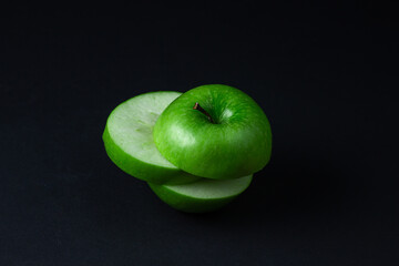 Green apple on a dark background. A cut green apple on a black background. Healthy food