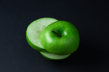 Green apple on a dark background. A cut green apple on a black background. Healthy food
