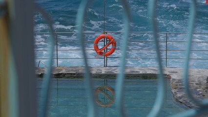 Un salvagente arancione sul bordo di una piscina in riva al mare.
