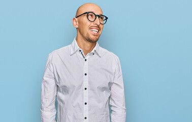 Bald man with beard wearing business shirt and glasses looking away to side with smile on face, natural expression. laughing confident.