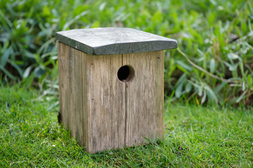 Close-up of a wooden bird house on grass.