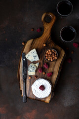 Different kinds of cheese on the wooden board with berries