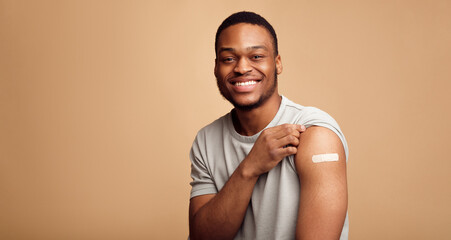 Portrait Of Vaccinated African Man Showing His Arm, Beige Background - obrazy, fototapety, plakaty