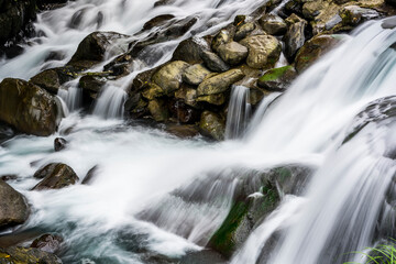 Fototapeta na wymiar Creek or stream water flowing past rocks and stones