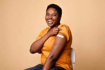 African Woman Showing Covid-19 Vaccinated Arm With Plaster, Beige Background