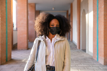 Young commuter woman in city in sustainable way wearing protective face mask against Coronavirus...