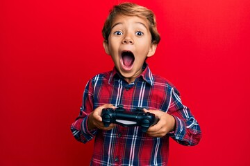 Adorable latin kid playing video game holding controller afraid and shocked with surprise and...