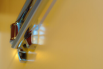 Close-up of a decorative element of the interior of a room - chrome-plated holder for towels (bathroom accessories) on yellow ceramic tiles