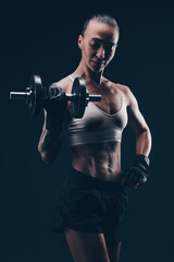 Fototapeta na wymiar Slim brunette girl in sportswear doing workout with a dumbbell. Fitness sexy girl pumping arms