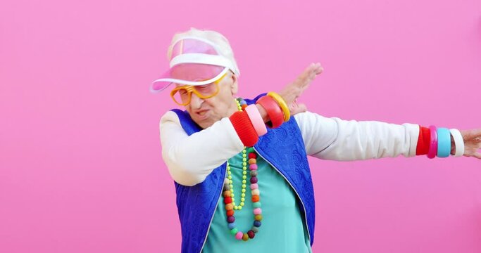 Footage of a funny grandmother with fashionable look acting on colored backgrounds