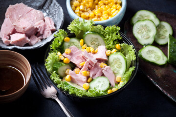 fresh tuna salad with corn and lettuce leaves, sauce and fresh cucumbers, closeup