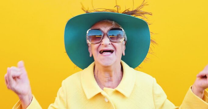 Footage of a funny grandmother with fashionable look acting on colored backgrounds