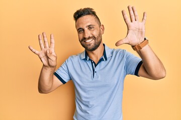 Handsome man with beard wearing casual clothes showing and pointing up with fingers number nine while smiling confident and happy.