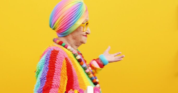Footage of a funny grandmother with fashionable look acting on colored backgrounds
