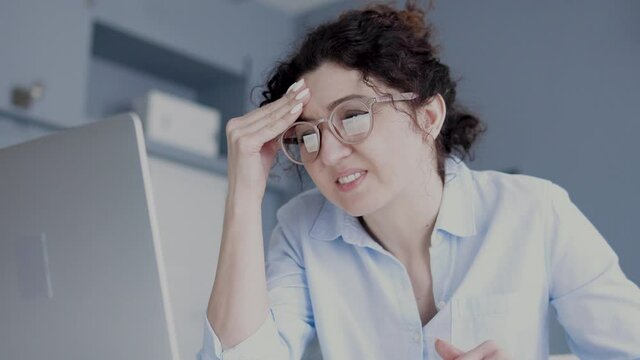 Tired business woman in eyeglasses suffering headache working on laptop, problem