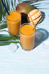 Glass of fresh mango juice cocktail and palm branches