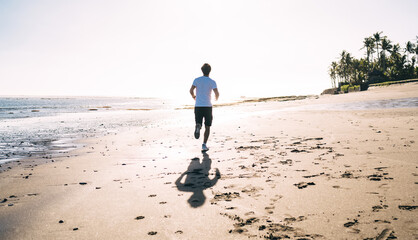 Unrecognizable man running on sandy beach