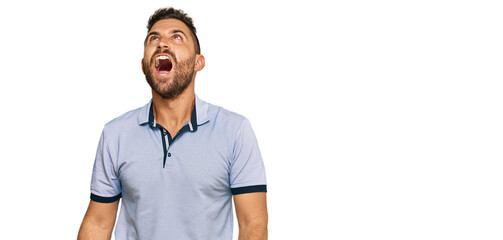 Handsome man with beard wearing casual clothes angry and mad screaming frustrated and furious,...