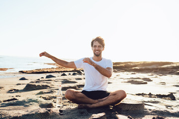 Fototapeta na wymiar Happy man meditating on sandy beach