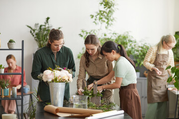 Diverse group of young florists creating floral compositions during workshop class, copy space
