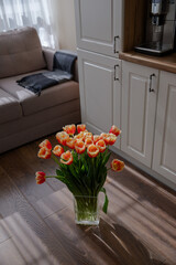 A bouquet of bright tulips on the kitchen floor. Tulips on the background of the home interior. Spring flowers. Fresh orange buds