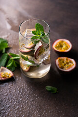 refreshing drink with passion fruit. cocktail with tropical fruit on a dark background. with green mint leaves. vertical position
