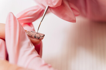 Manicure process. The master draws a butterfly drawing on the fingernail with a thin brush.