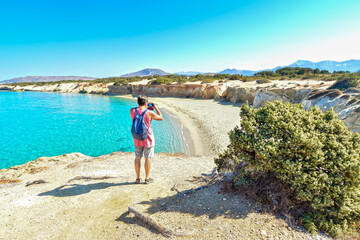 Traveller on a lonely beach takes photos with his smartphone
