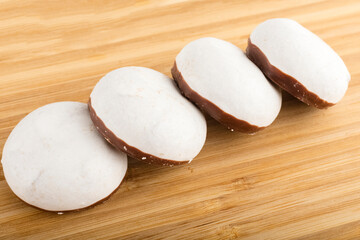 Gingerbread in white glaze with chocolate, on wooden table background. Sweet Deassert to tea