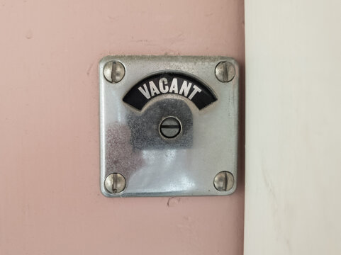 Vacant sign on a pink toilet door.